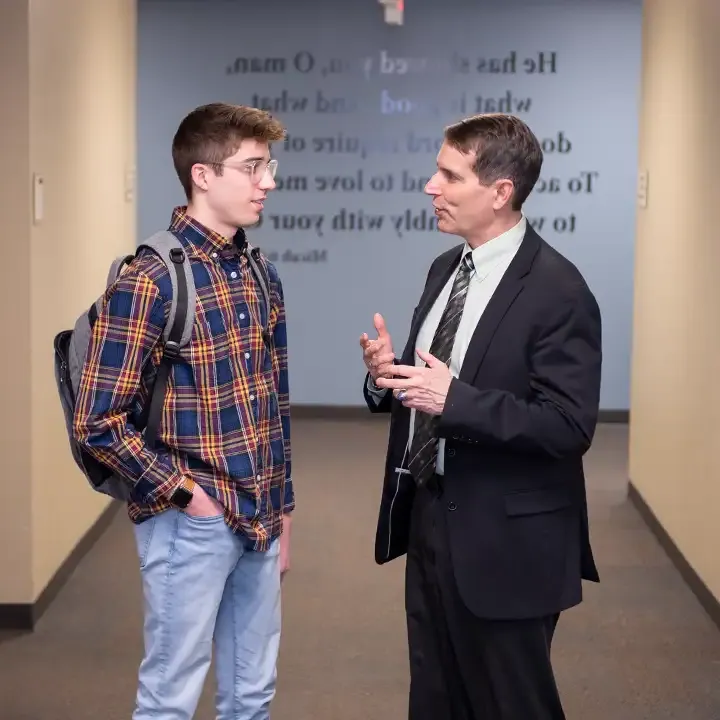 Two men talking in a hallway